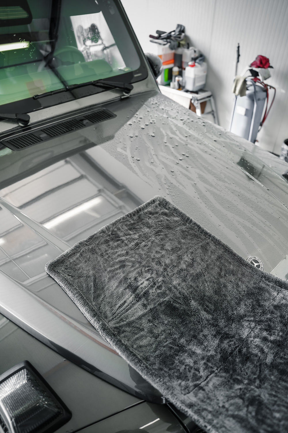 Grey 1600 GSM drying towel on a bonnet showing a dried area beside remaining water droplets
